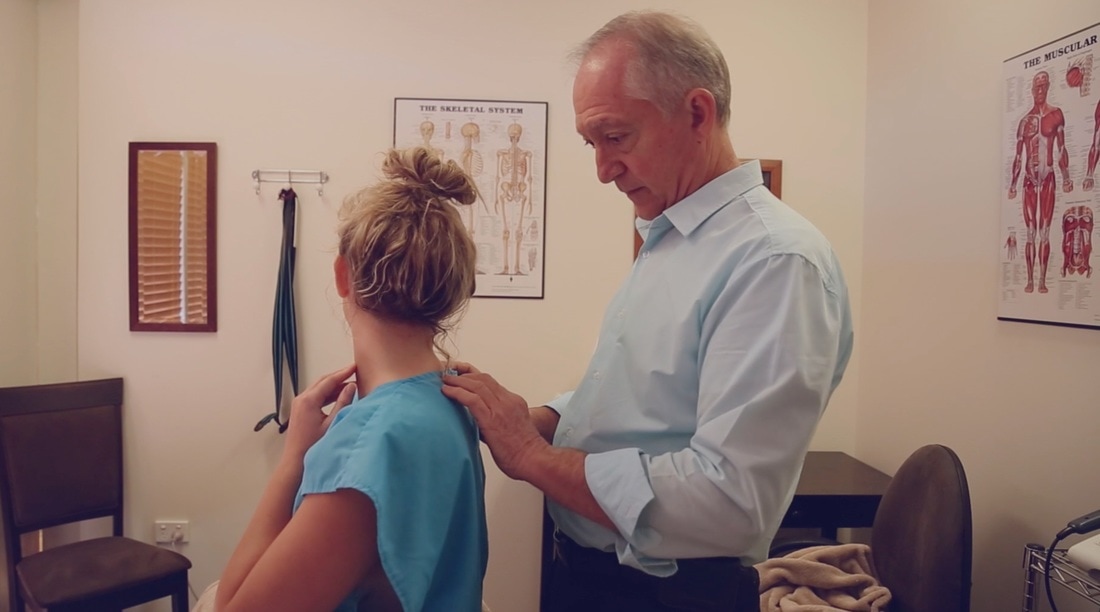 Malcolm Hampson consulting with a patient about neck pain